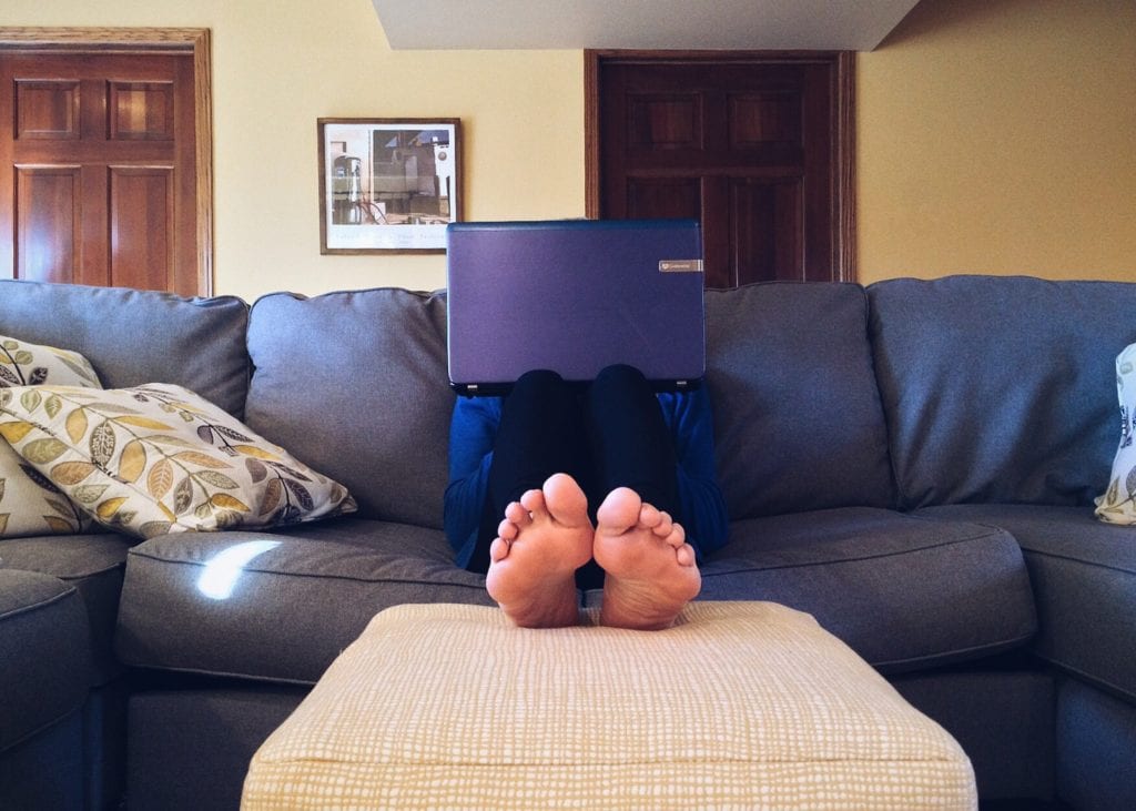 A Person is sitting on the couch with a computer
